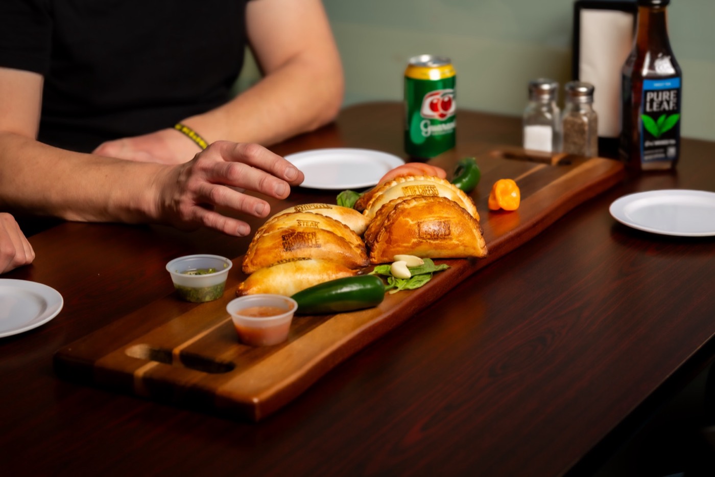 Two people sharing a board of empanadas at a table